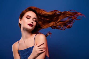 Modaya uygun muhteşem rüya gibi bayan ünlünün mavi arka planda kendini kucaklamasının fotoğrafı..