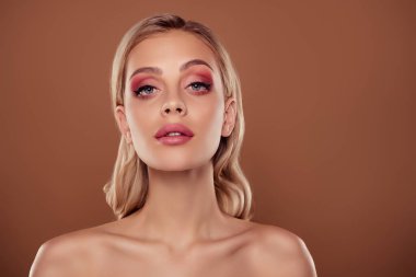 Pembe makyajlı bir kızın fotoğrafı. Göz gölgesi, izole edilmiş pastel kahverengi arka plan..