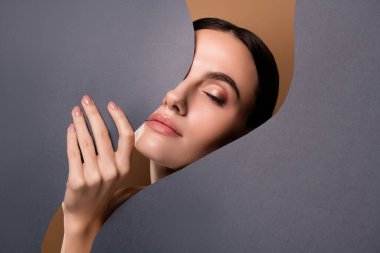 Gri arkaplanda izole edilmiş kağıt pankart tutan nazik, nazik, kapalı gözlü bir kadının fotoğrafı..