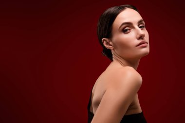 Çekici, şık bir bayanın fotoğrafı poz veriyor. Kırmızı, boş alan arkaplanının yanında siyah bir elbise giyiyor..