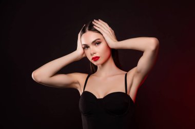 Siyah gecelikli kadının fotoğrafı. Kahverengi saçlı, koyu renk arka planda..