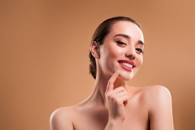 Neşeli, sağlıklı, güzel bir modelin fotoğrafı. Dokunaklı bir çene. Bej renkli arka planda izole edilmiş boş bir alan..