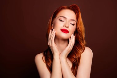 Çekici, çekici, kapalı gözlerinin fotoğrafı kahverengi arka planda izole edilmiş pürüzsüz tenin tadını çıkarıyor..