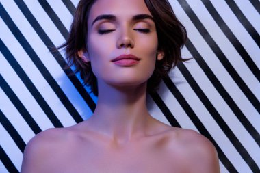 Çekici, güzel bir kadının, kapalı gözlerinin, çıplak omuzlarının, çizgili arka planda izole edilmiş, şehvetli bir fotoğrafı..