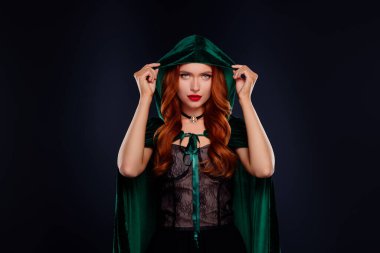 Kötü büyücü kızın fotoğrafı yeşil başlık takıyor. Tehlikeli, izole, siyah bir arka plan..