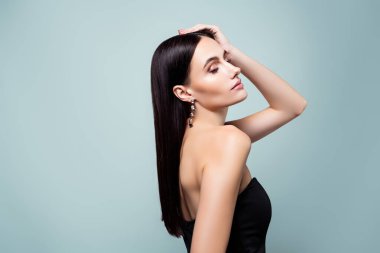 Çok güzel bir bayanın poz verirken çekilmiş fotoğrafı. Siyah elbise giymekten keyif alıyor. Gri renkli arka plan..