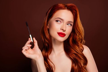 Çekici bir kadının uzun kirpiklerini sürerken çekilmiş fotoğrafı. Kahverengi arka planda izole edilmiş boş bir alan..