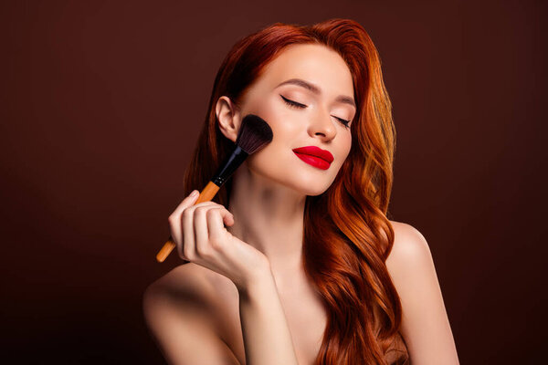 Photo of stunning rich lady model applying foundation highlighter isolated on brown color background.