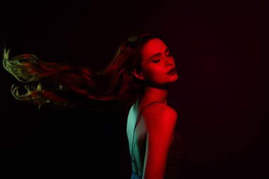 Koyu kırmızı neon arka planda izole edilmiş göz kamaştırıcı muhteşem kadının fotoğrafı..