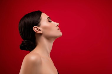 Profil tarafı fotoğrafı. Gözleri kapalı muhteşem bir kadın. Kırmızı arka planda vücut ferahlığını hisset..