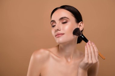 Çekici, güzel bir bayanın, doğal efekt sürerken çekilmiş fotoğrafı. Renkli arka planda izole edilmiş doğal bir makyaj..