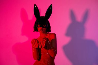 Çekici kadın eli pençeleri rol yapıyor tavşan maskesi neon ışıklı arka planda izole edilmiş kırmızı deri kıyafetler..
