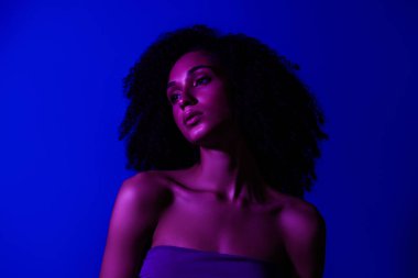 Çekici bir kızın fotoğrafı. Elbise giysisi, profil tarafı. Mavi neon rengi arka plan..