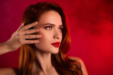 Çekici ve güzel bir kadının fotoğrafı boş görünüyor. Kırmızı arka planda izole edilmiş omuzları kaldıran uzay dokunuşu yüzü..