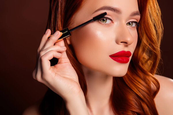 Close up photo of gorgeous attractive lady applying mascara make up isolated on brown color background.