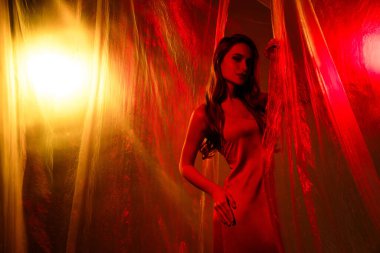 Çekici bir bayan tiyatronun fotoğrafı. Kırmızı arka planda izole edilmiş seksi elbiseler giymiş aktris..