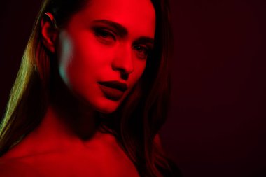 Çekici, baştan çıkarıcı, güzel bayanın fotoğrafı koyu kırmızı neon arka planda izole edilmiş..