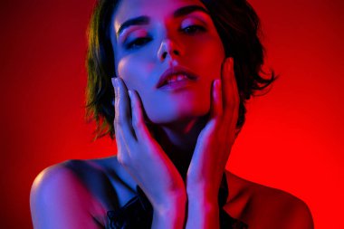 Çekici kadın dokunuşunun fotoğrafı kırmızı neon arka planda izole edilmiş mahrem anın tadını çıkarıyor..