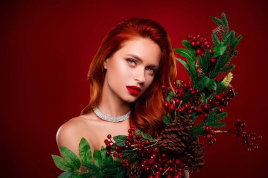 Çekici kadının fotoğrafı baştan çıkarıcı hissediyor. Kırmızı arka planda ökseotu dekoru olan yeni yıl ruhunun tadını çıkar..