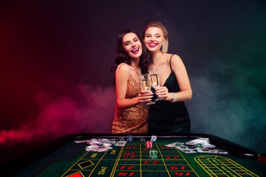 Çekici ve şık kadınların içki içip VIP kumarhanesinde riskli bahisleri kazanmalarını kutlayan bir fotoğraf..