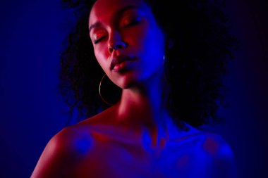 Çekici, güzel, çıplak bir kadının fotoğrafı. Gözleri kapalı, mavi neon renkli arka planda izole edilmiş..