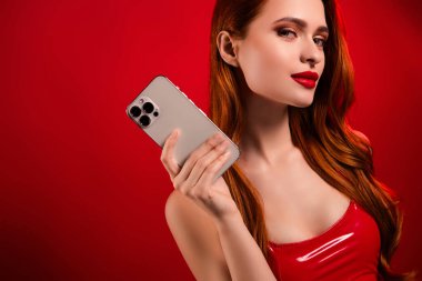 Çekici, muhteşem bir kadının fotoğrafı. Telefon duruşu, eshop. Kırmızı arka planda izole seksi deri kıyafetler..