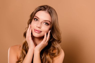 Çok tatlı bir kızın bej renkli arka planda izole edilmiş sağlıklı ve temiz bir cilt boşluğunun keyfini çıkardığı bir fotoğraf..