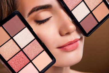 Çekici bir kadının göz farı sürerken çekilmiş resmi izole edilmiş bej arka plan..