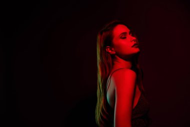 Göz kamaştırıcı rüya gibi bir kız arkadaşın fotoğrafı. Gözler kapalı. Koyu kırmızı neon arka planda izole edilmiş boş bir alan..