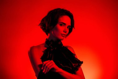 Çekici ve çekici bir kadının kırmızı neon arka planda izole edilmiş bir gece kulübündeki kutlama partisinin fotoğrafı..