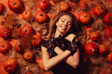 Aristokrasi stili elbise giymiş mutlu bayan gençliğin en iyi fotoğrafı Cadılar Bayramı balkabaklarının yanında uzanan kendine dokunuşun..