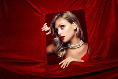 Deliğin içindeki çekici modelin fotoğrafı kırmızı kadife renkli arka planda izole edilmiş güzellik ürünlerinin reklamını yapıyor..