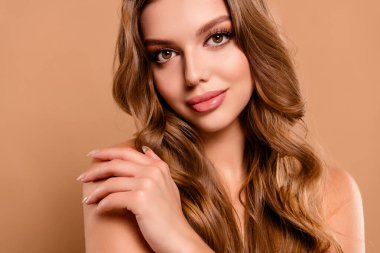 Çekici, alımlı, güzel bir kızın bej renkli arka planda çıplak omuzlarını kucaklaması..