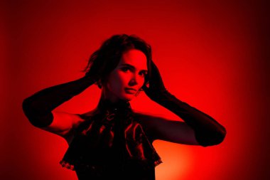 Şehvetli kızın portresi zarif bir şekilde klasik tarzda poz veriyor koyu kırmızı arka planda izole edilmiş..