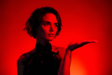 Eskimiş giysili çekici bir kadının fotoğrafı. Koyu kırmızı arka planda boş bir alan tutuyor..