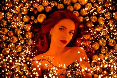 Baloların arasında yatıp, çeşitli xmas aksesuarlarını tanıtan güzel, lüks bir bayanın fotoğrafı..