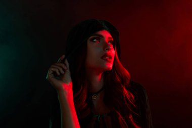 Güçlü cadı kadının başlığa dokunuşunun fotoğrafı neon sis filtresiyle kırmızı renk boş alan arkaplanına bak.