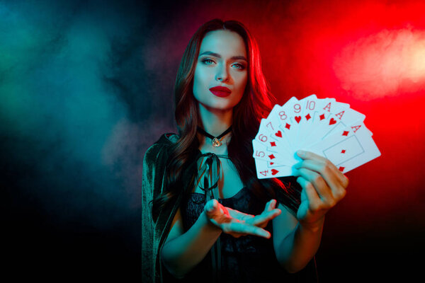 Photo of lady wear dark witch costume cape show poker cards combination isolated neon mist filter color background.