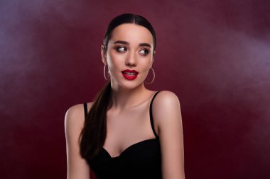 Güzel bir genç kızın resmi. Boş bir uzay promosyonu. Kestane renkli arka planda siyah bir elbise giy..