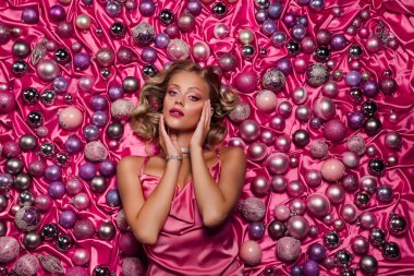 Parlak pembe aksesuarların üzerinde duran muhteşem genç bayan modelin yeni yıl ağacının düz tablosu..