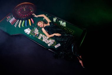 Üst manzara fotoğrafı şık pullu elbise yığının yanında tatmin olmuş para ve çipler yeşil duman arka planda izole.
