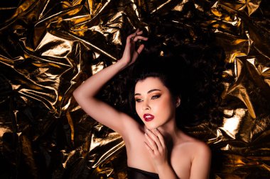 Altın folyo rengi arka planda izole edilmiş mükemmel makyajlı çekici bir kızın yüksek açılı fotoğrafı..