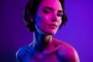 Çekici kızın fotoğrafı göz altlarında kolajen pedlerle izole edilmiş çok renkli neon arka plan..
