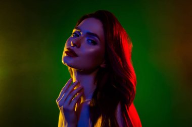 Göz kamaştırıcı bir kadının boynuna dokunduğu fotoğraf çekici, soyutlanmış, neon ışık efekti arka planında..