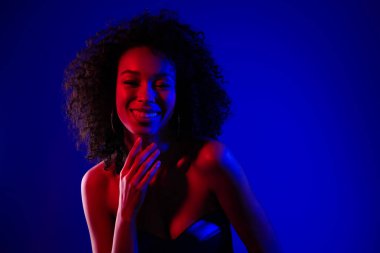 Göz kamaştırıcı, mutlu, güzel bir modelin fotoğrafı. Kahkahalar atan özel bir kulüp partisi. Mavi neon renkli arka plan..