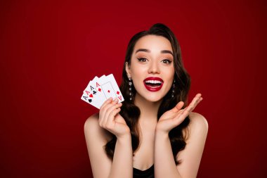 Çarpıcı mutlu bayan poker oyuncusu kırmızı renkli arka planda izole edilmiş poker gecesini kazanıyor..