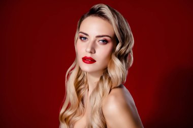 Parlak makyajlı bir kadın portresi. Sarı bukleli, izole edilmiş kırmızı arka planlı..