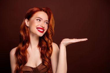 Kahverengi arka planda izole edilmiş boş bir alan sunan büyüleyici, mutlu model kadının fotoğrafı..