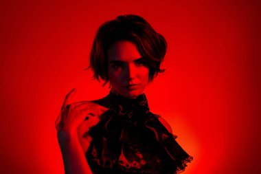 Kırmızı neon arka planda izole edilmiş zarif ve çekici bir bayanın VIP gece kulübü pozu..