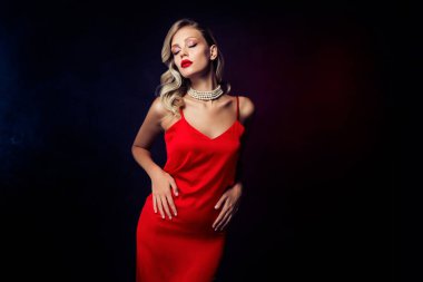 Göz kamaştırıcı tutkulu Hollywod bayanın fotoğrafı koyu renk arka planda izole edilmiş kırmızı elbise poz veriyor..